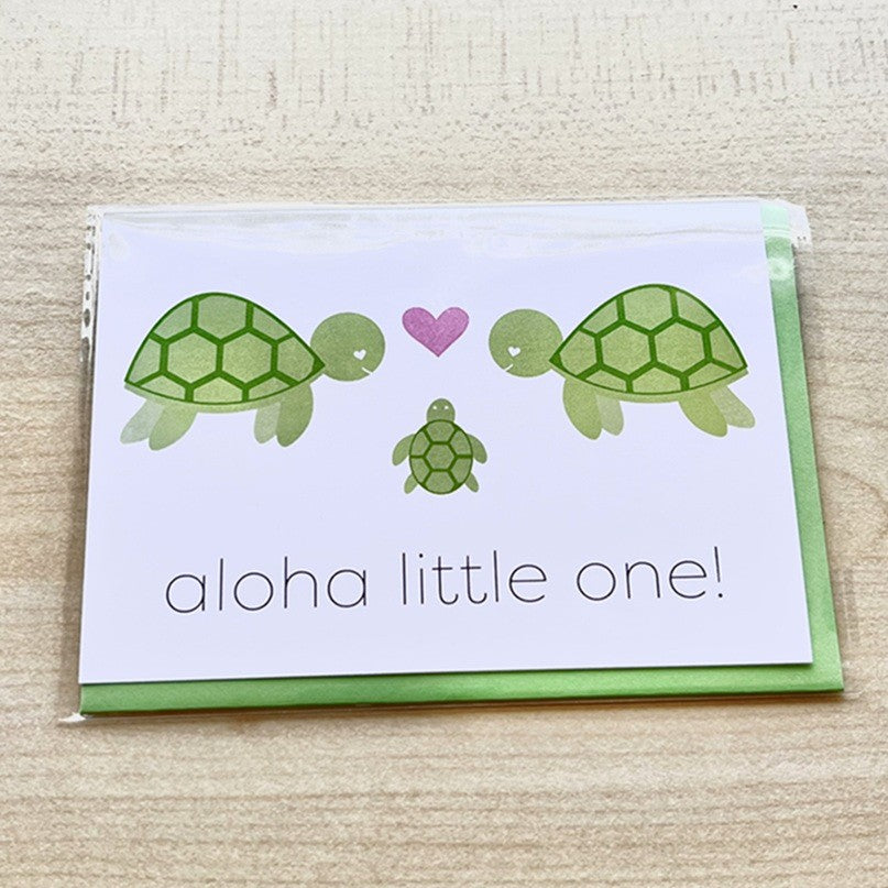 Greeting card with turtle illustrations and 'aloha little one!' text on a wooden surface