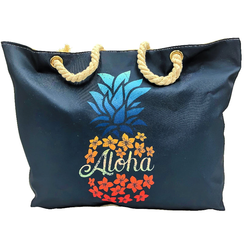 black beach bag with a printed polyester front featuring a pineapple and flowers, and a cream colored canvas back. The bag has two handles and is closed with a zipper.