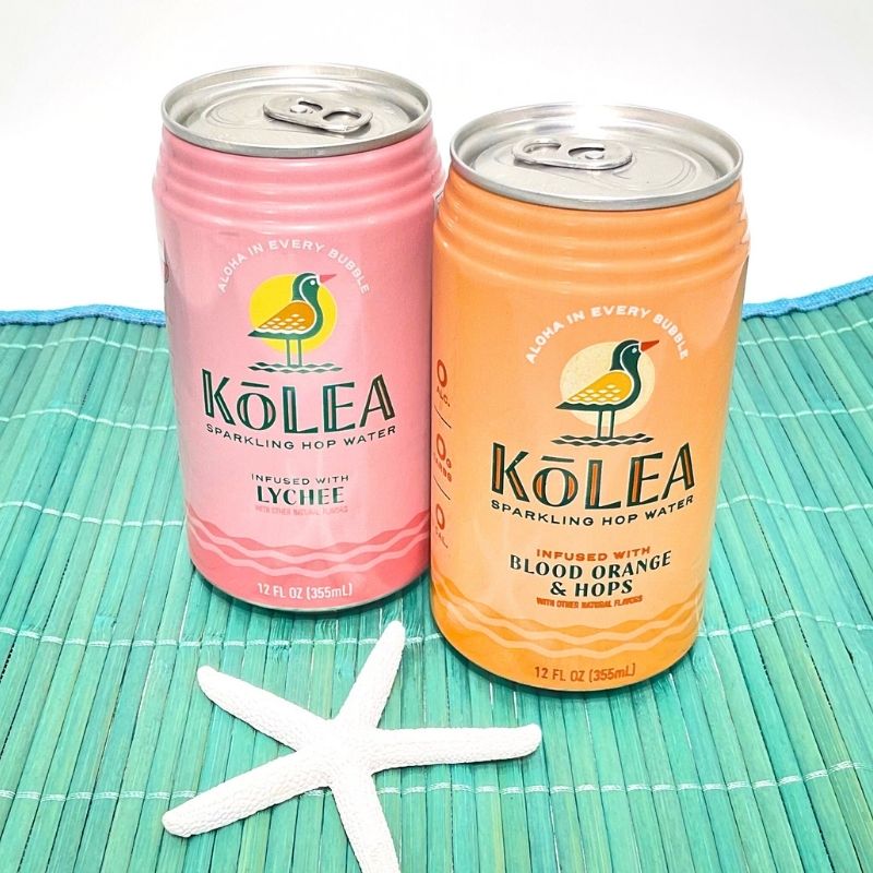 Two cans of Kolea sparkling hop water on a green mat with a starfish.
