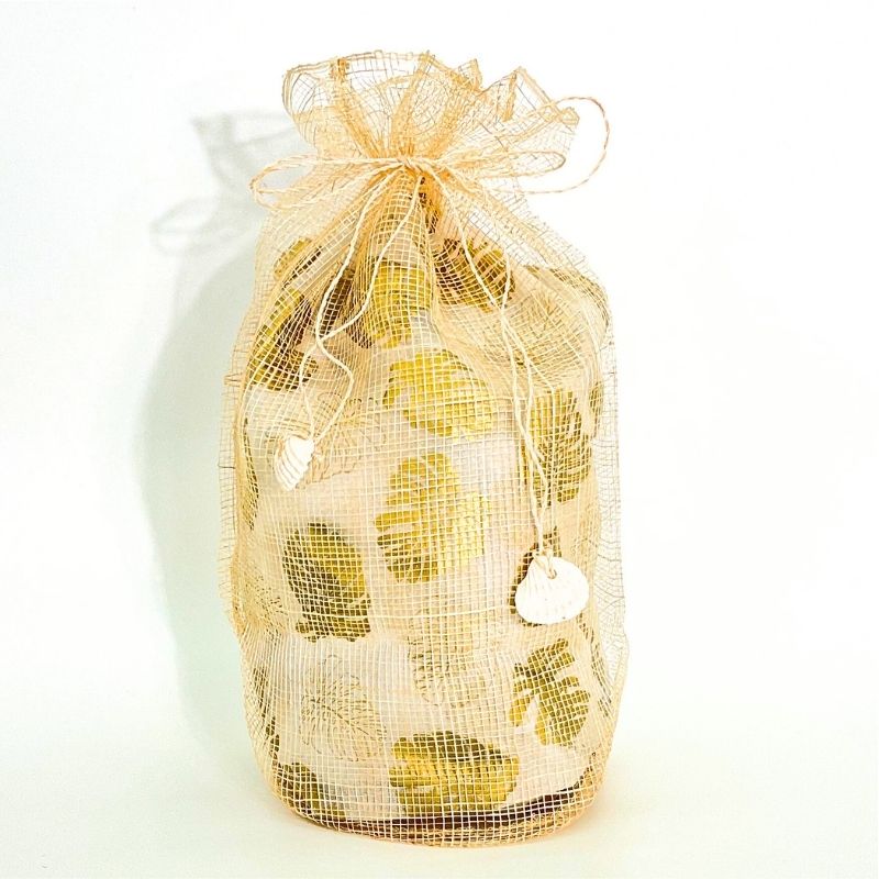 Gold mesh bag filled with green lemons on a white background