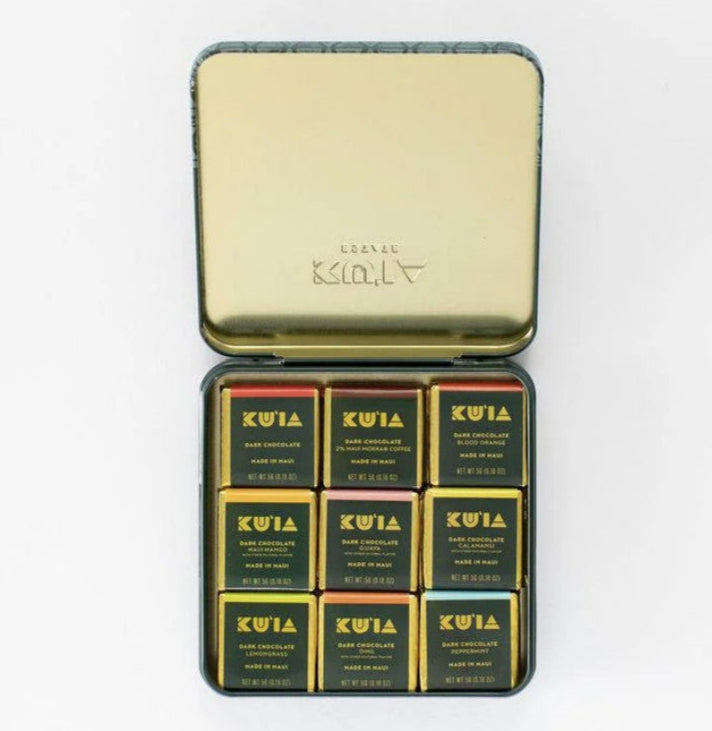 Gold tin containing KUIA chocolate bars on a white background