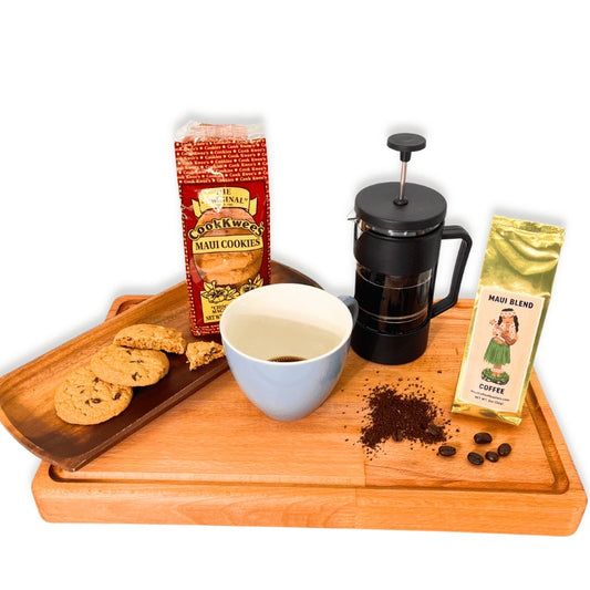 Coffee-making setup with a French press, coffee beans, cookies, and Maui cookies packaging on a wooden tray.