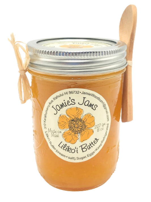 A jar of Lilikoi Butter with a label that reads 'Jamie's Jams - Lilikoi Butter'. There is a wooden spoon next to the jar.