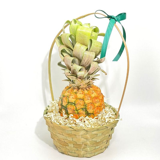 Fresh pineapple in a woven basket with a green ribbon on a white background