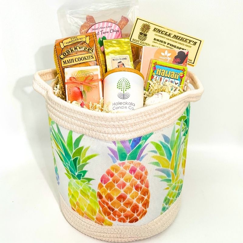 Colorful pineapple-patterned gift basket with various snacks on a white background