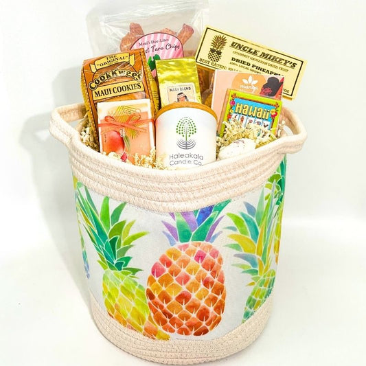 Colorful pineapple-patterned gift basket with various snacks on a white background