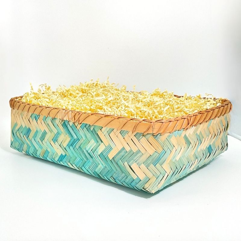 Woven basket with a zigzag pattern filled with yellow flowers on a white background