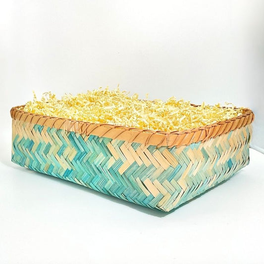 Woven basket with a zigzag pattern filled with yellow flowers on a white background
