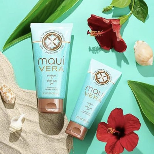 Two Maui Vera sunburn after sun gel tubes on a sandy surface with red flowers and green leaves.