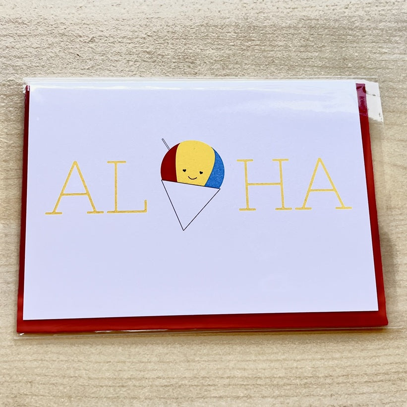 Card with 'ALOHA' text and a smiley beach ball design on a wooden surface